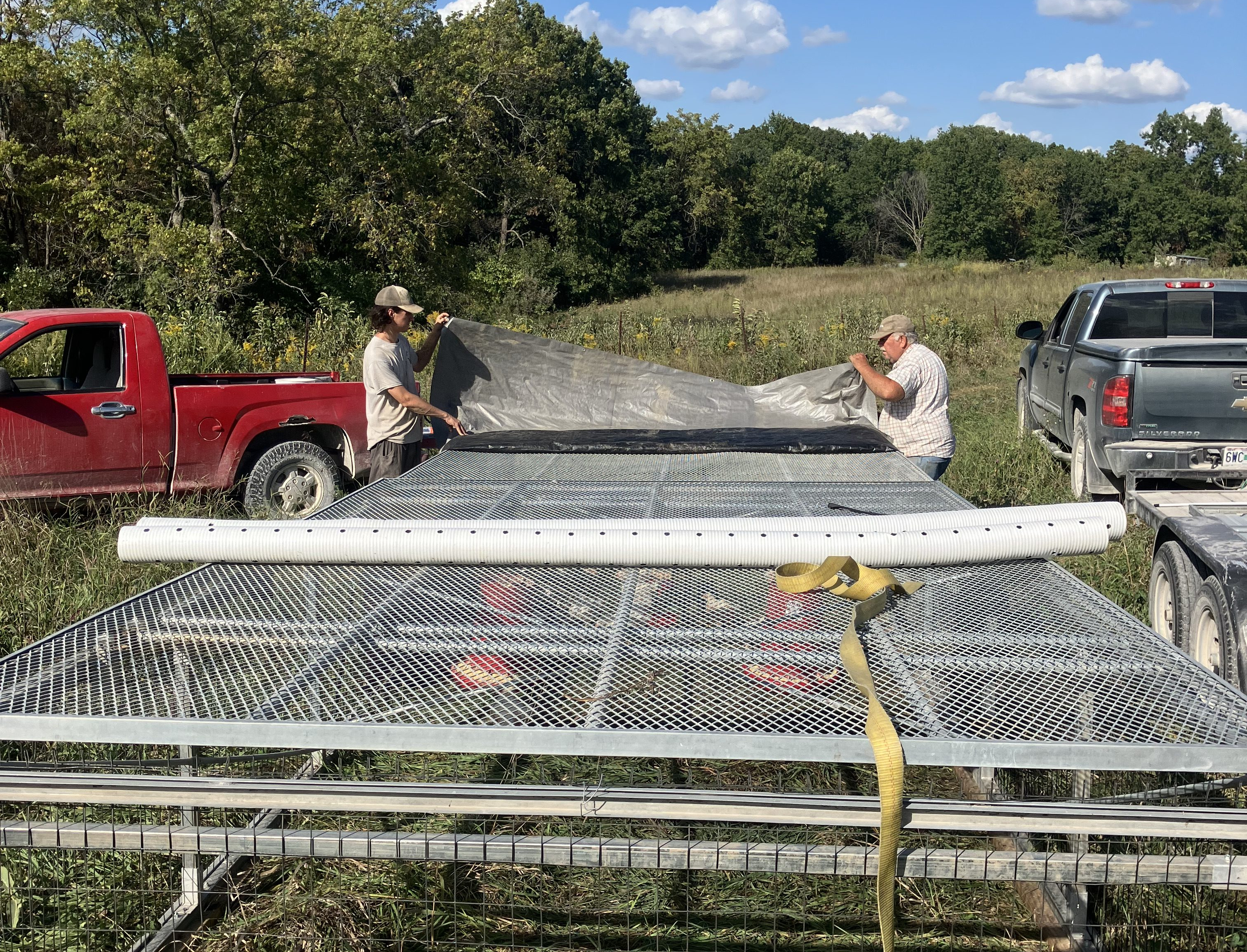 two men taking tarp off of chicken protector